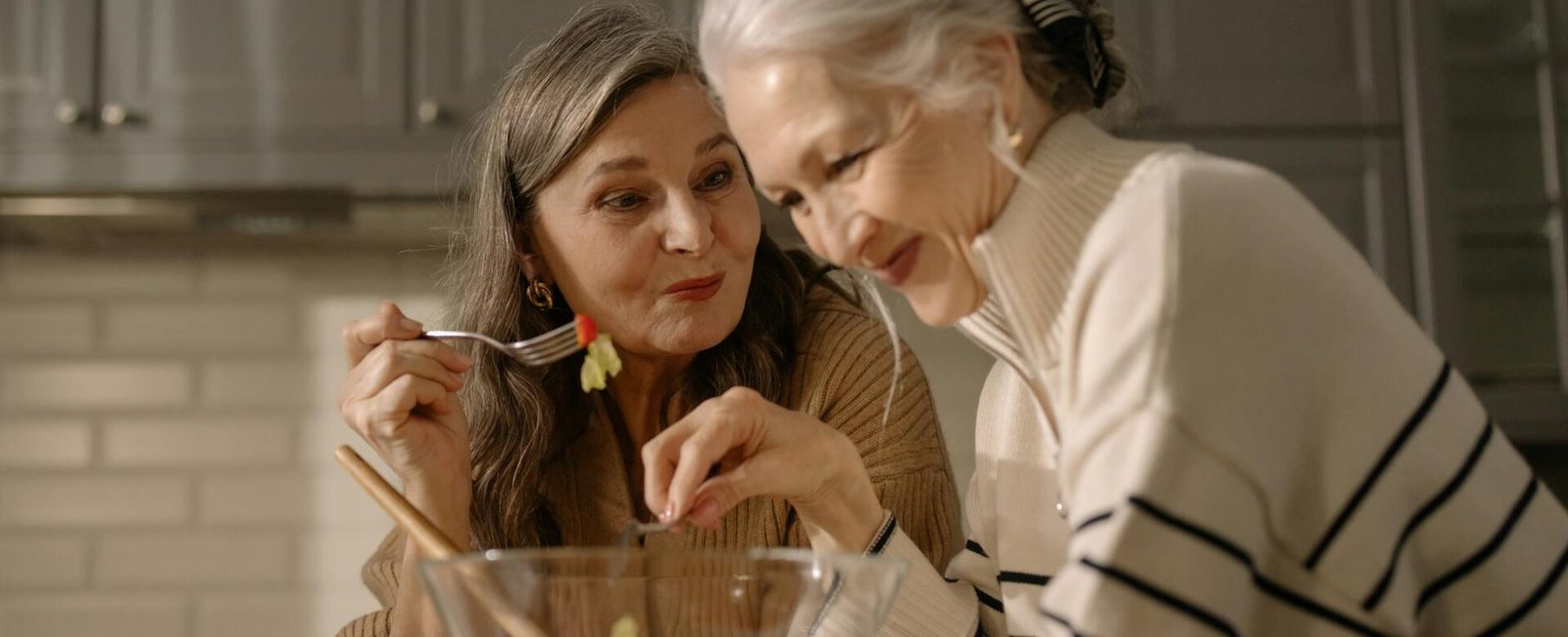 an elderly women eating salad in the kitchen